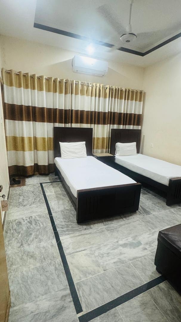 Twin Room at New Palace Guest House Islamabad with two single beds and air conditioning